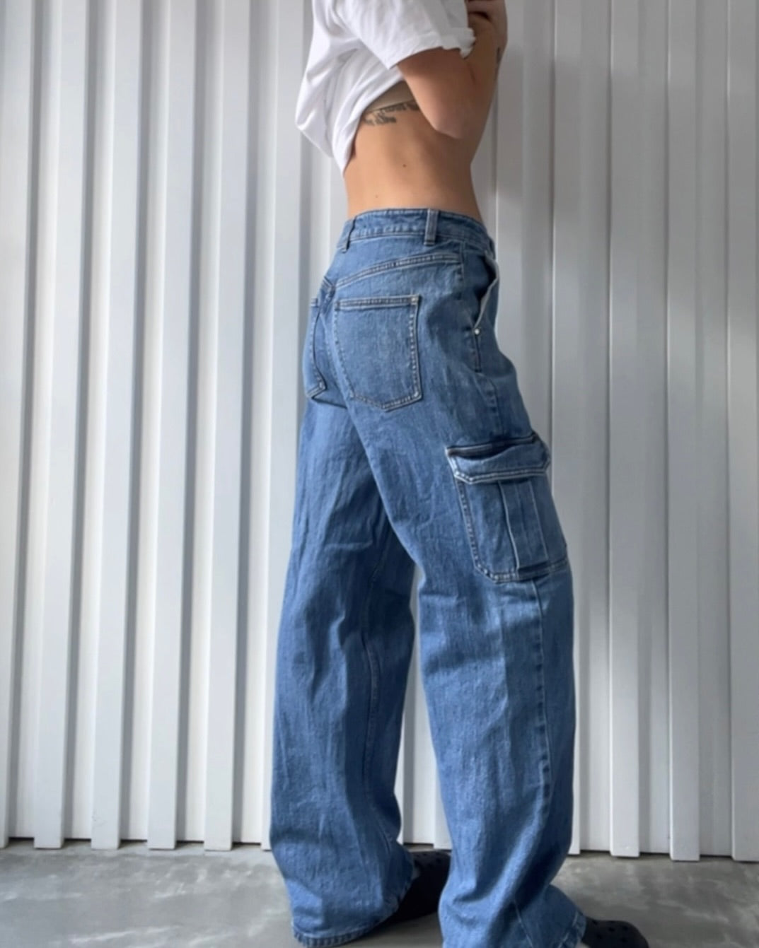 A person models a pair of baggy blue low-rise jeans against a white background